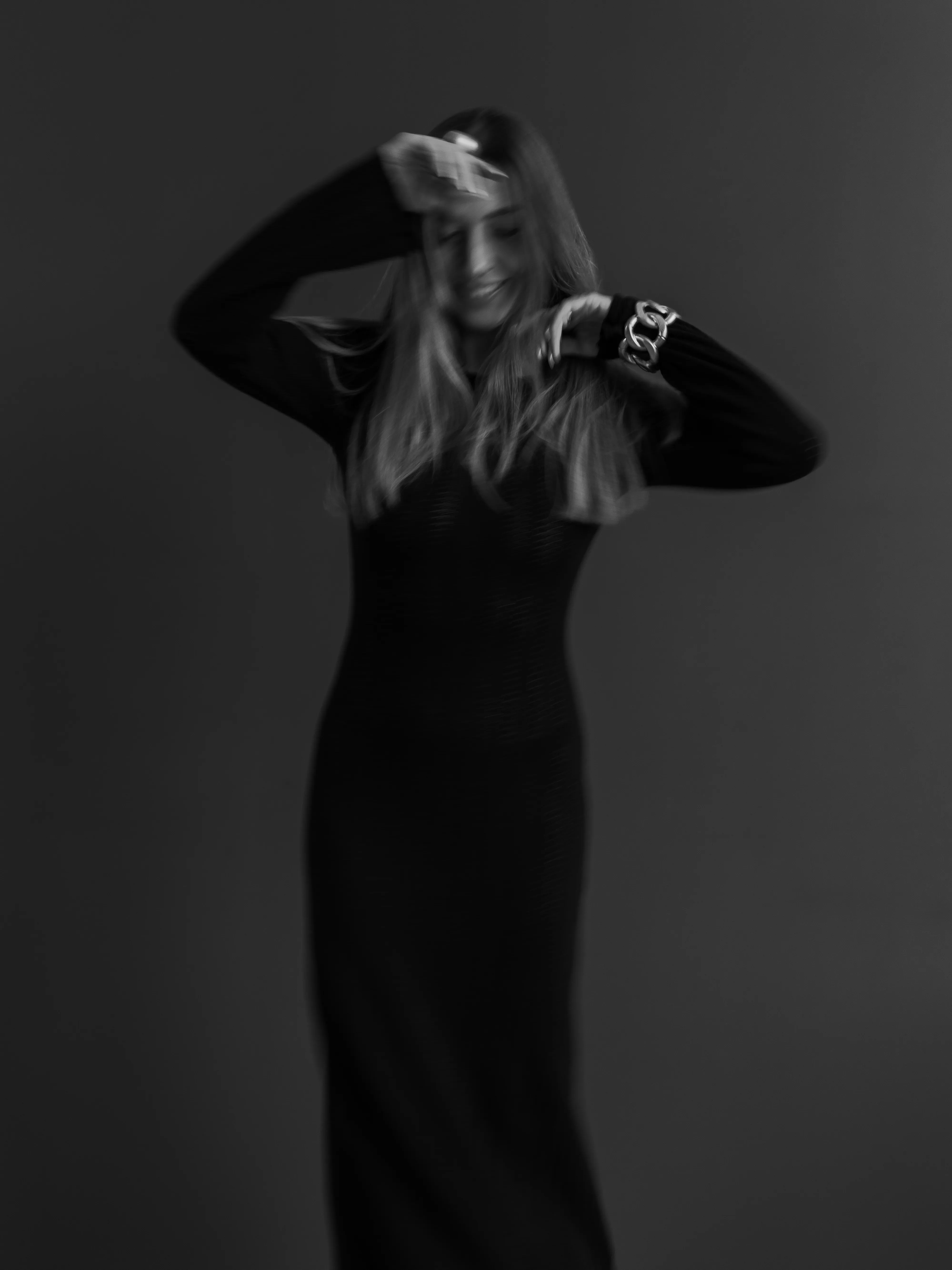Woman in black knit dress with motion blur, arms raised