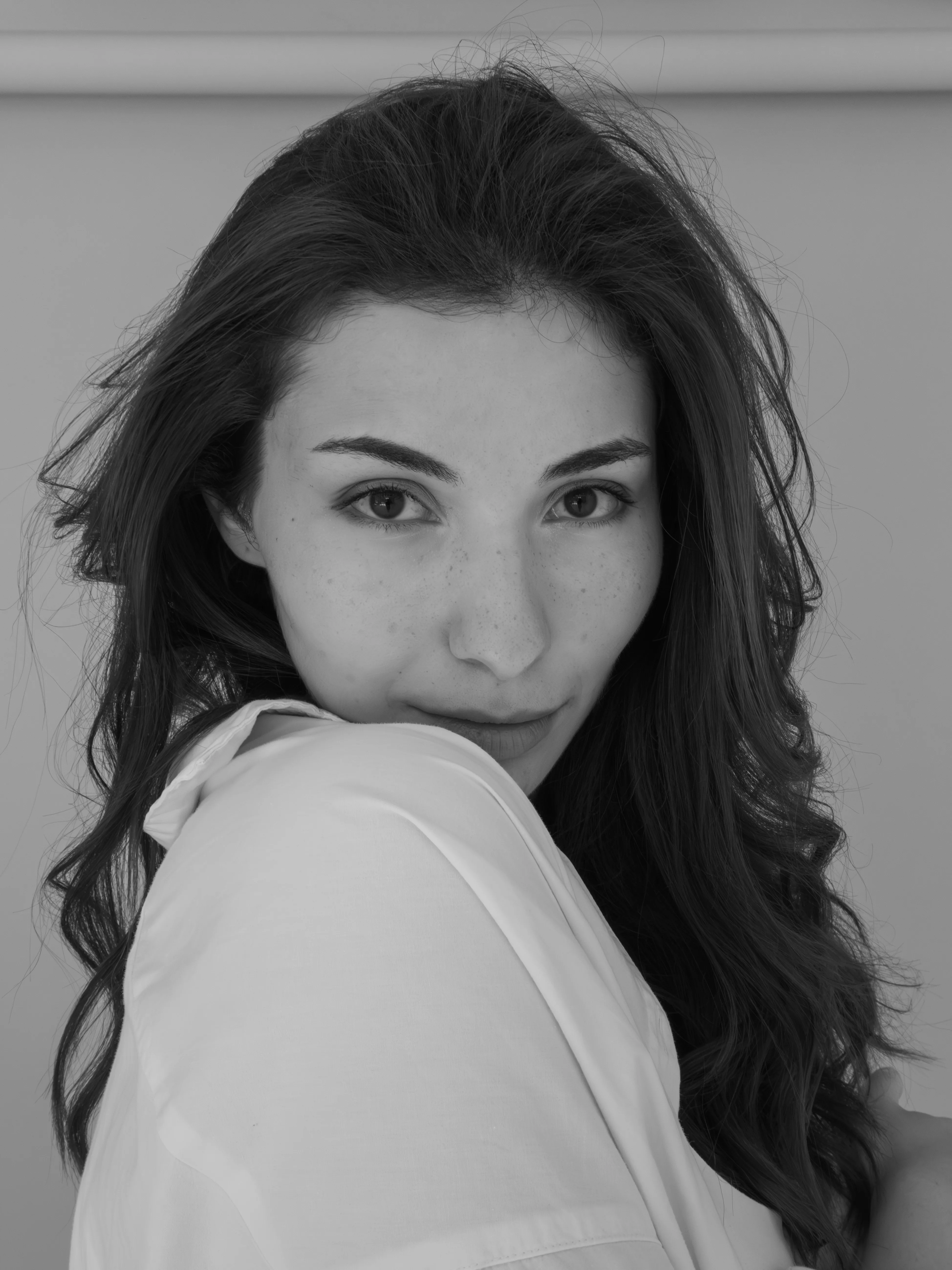 Portrait of woman with dark curly hair in white shirt