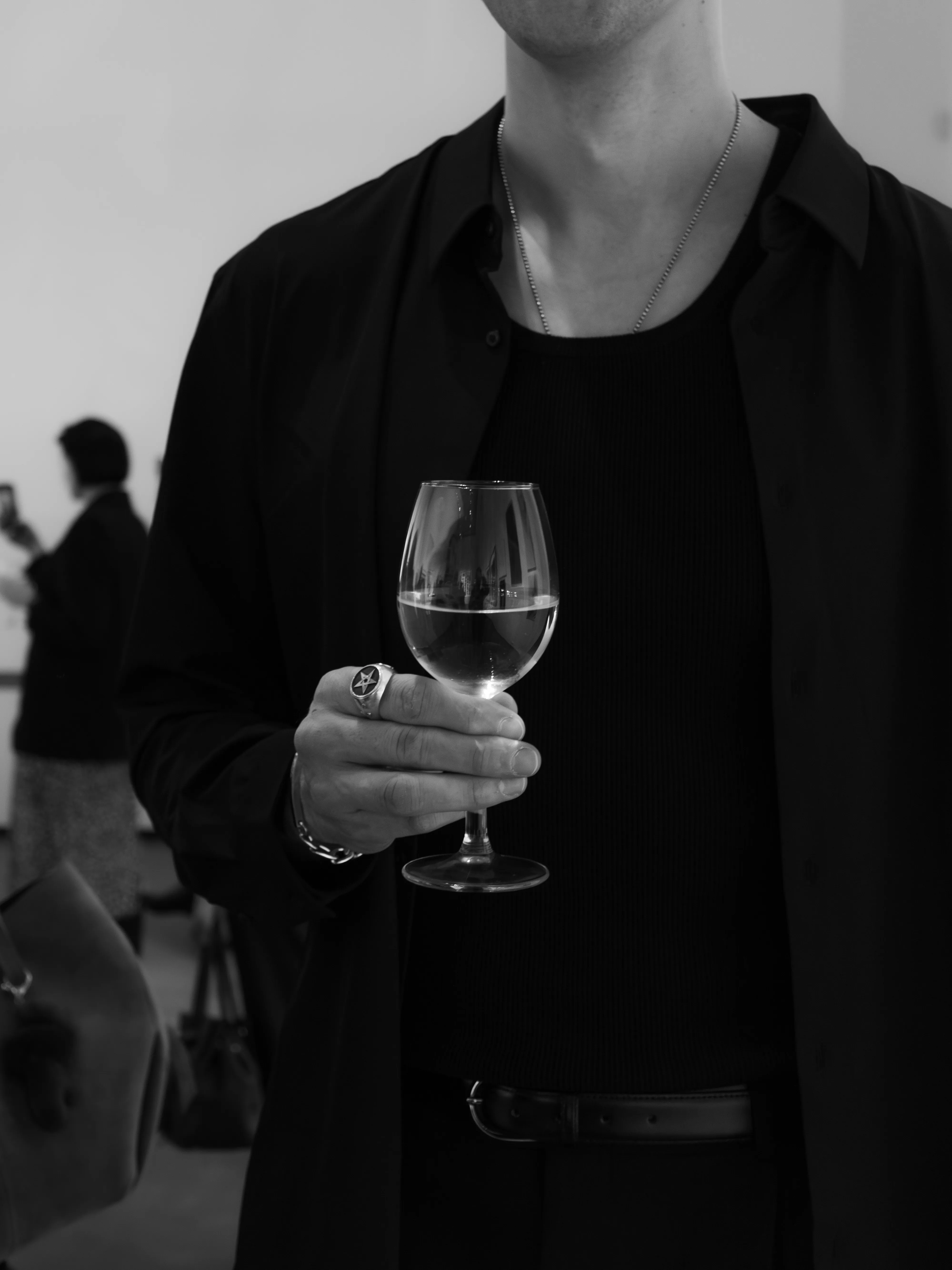 Man in black holding wine glass at gallery opening