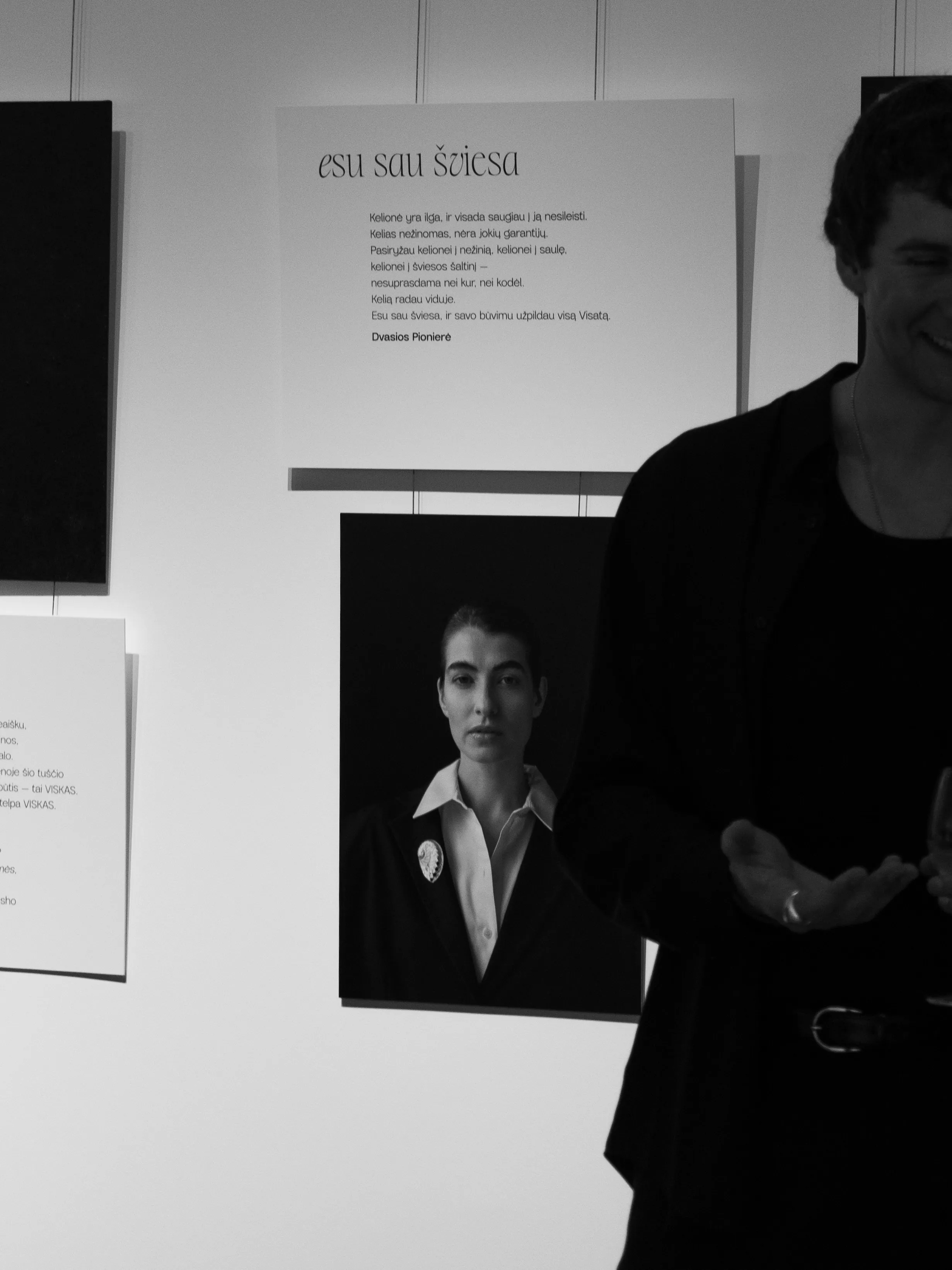 Man gesturing beside portrait and poetry display