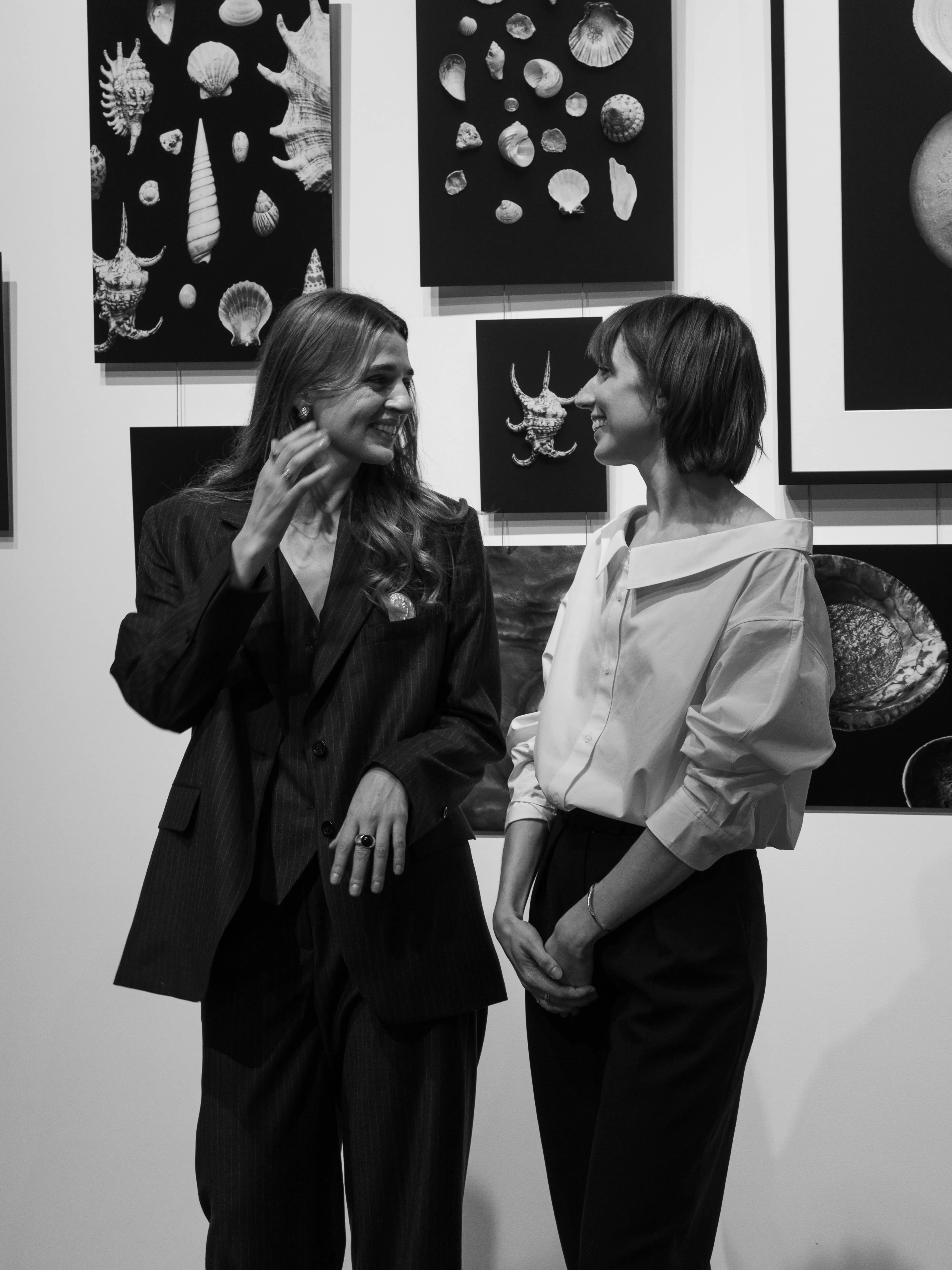 Two women laughing together at gallery opening