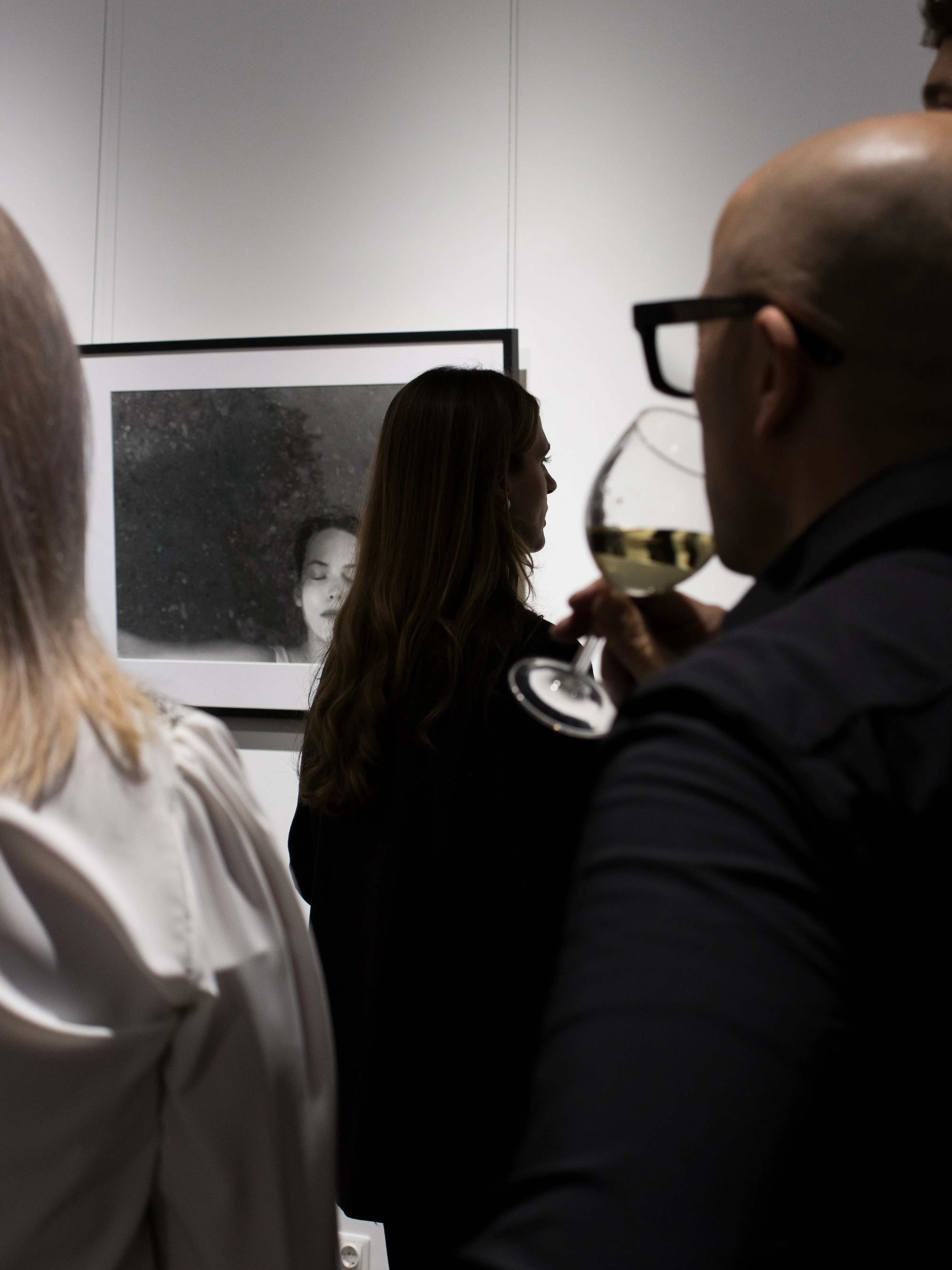Gallery visitors viewing portrait photography with wine