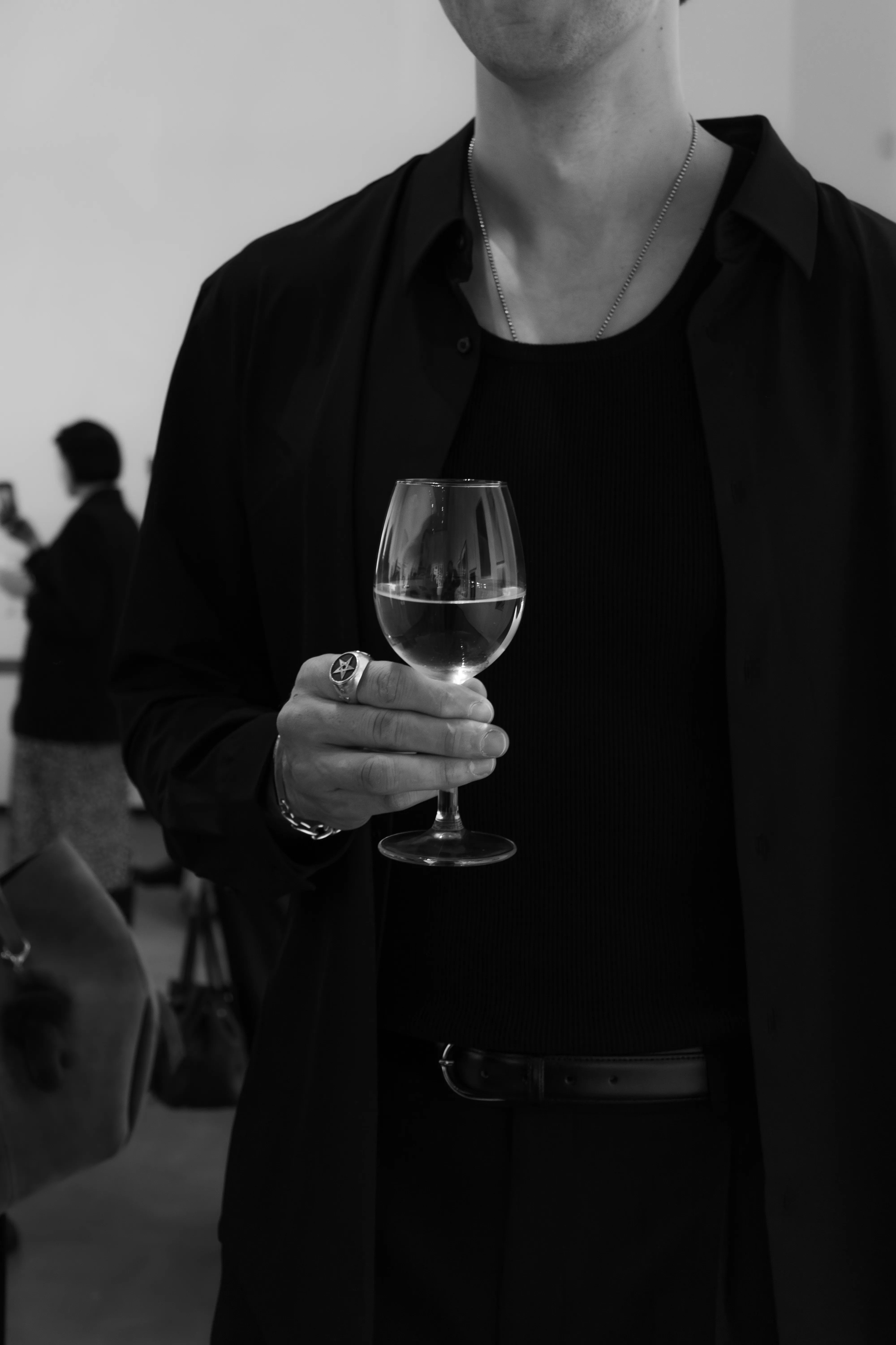 Man in black holding wine glass at gallery opening