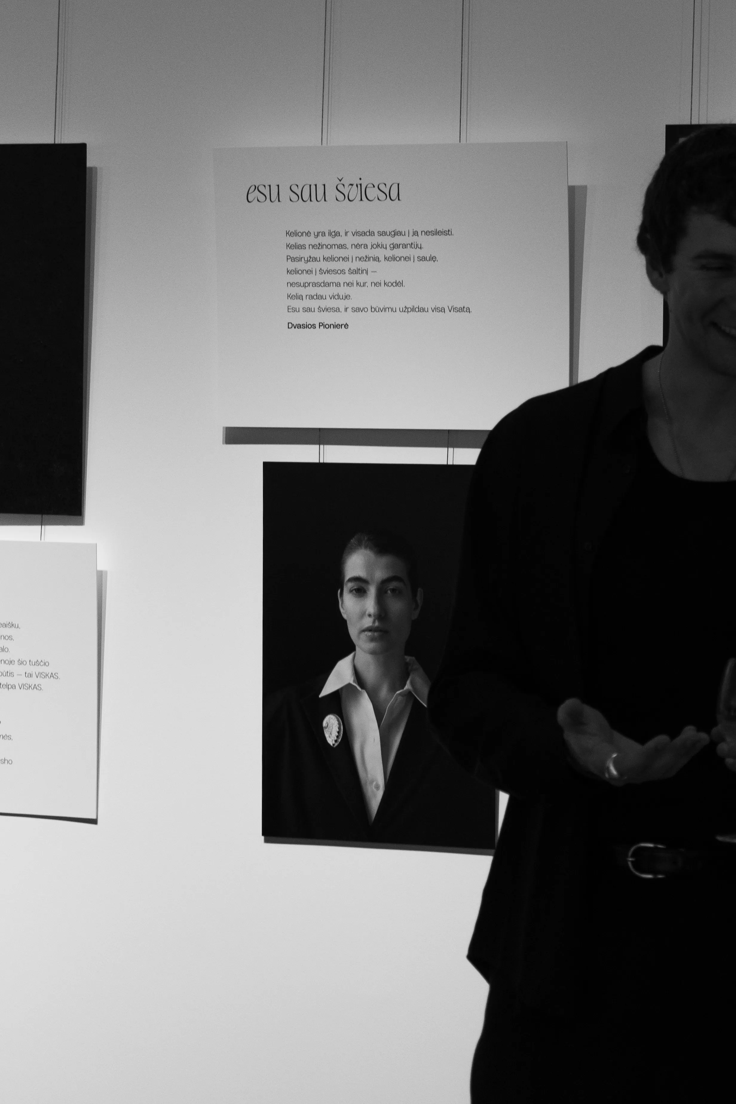 Man gesturing beside portrait and poetry display