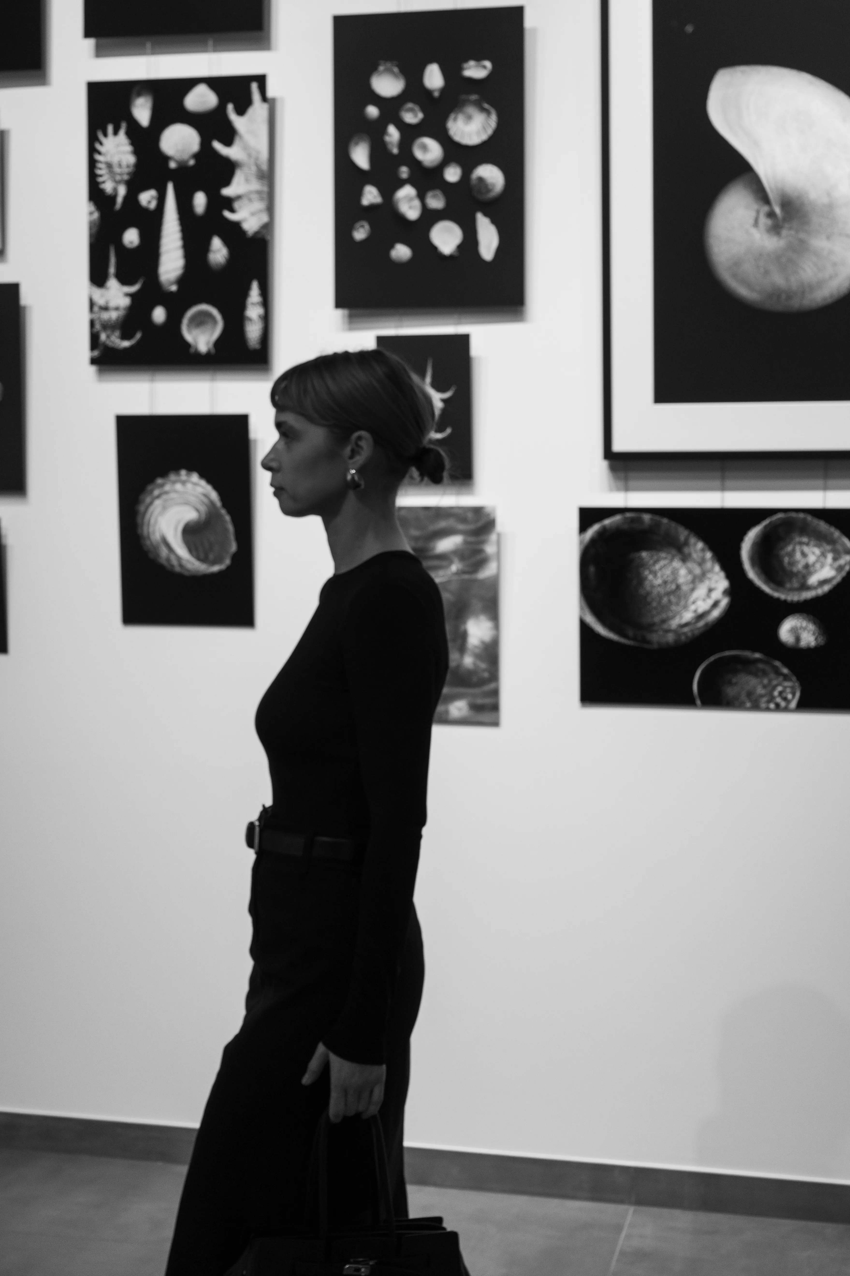 Woman in black contemplating seashell artwork