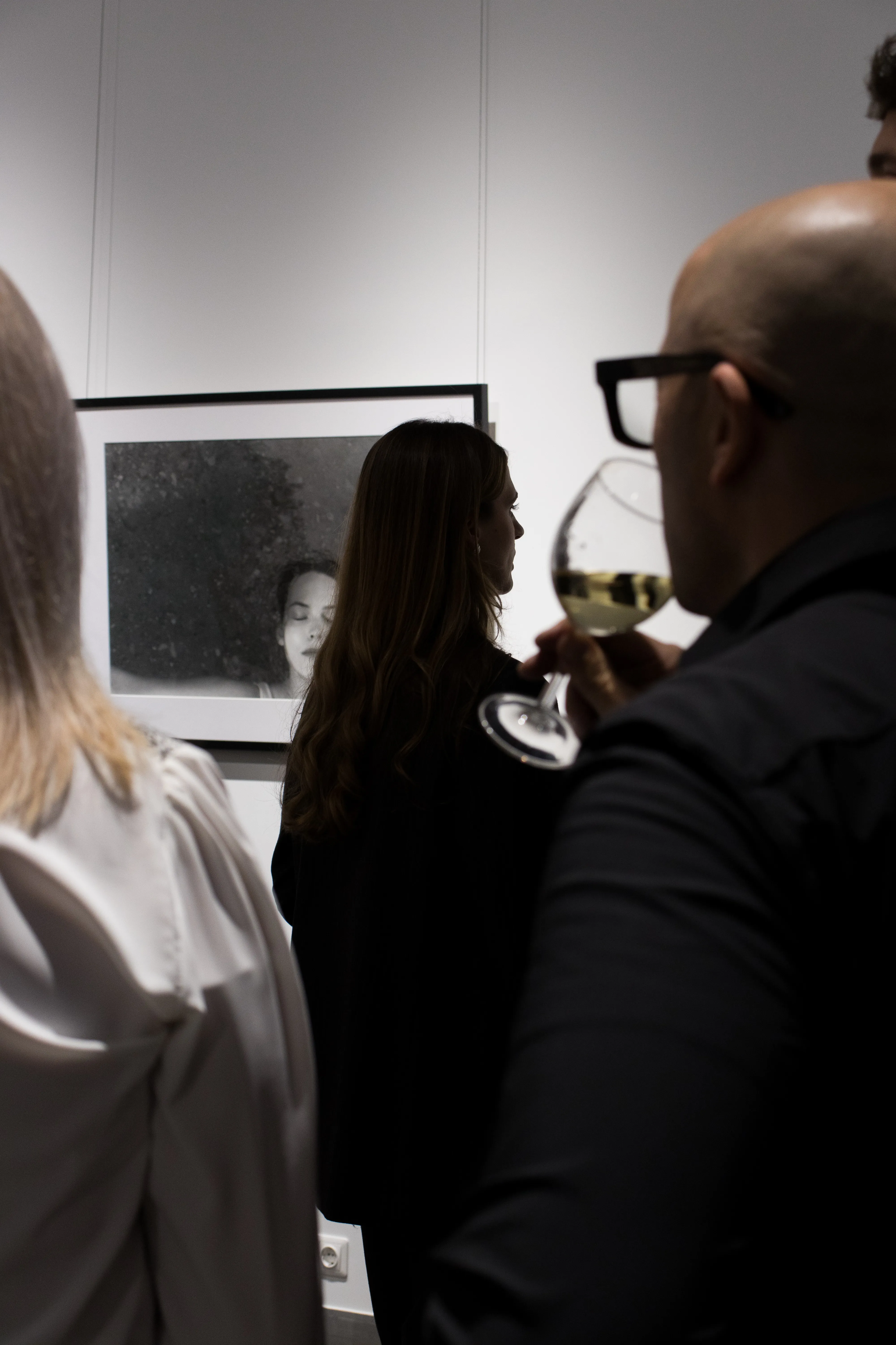 Gallery visitors viewing portrait photography with wine