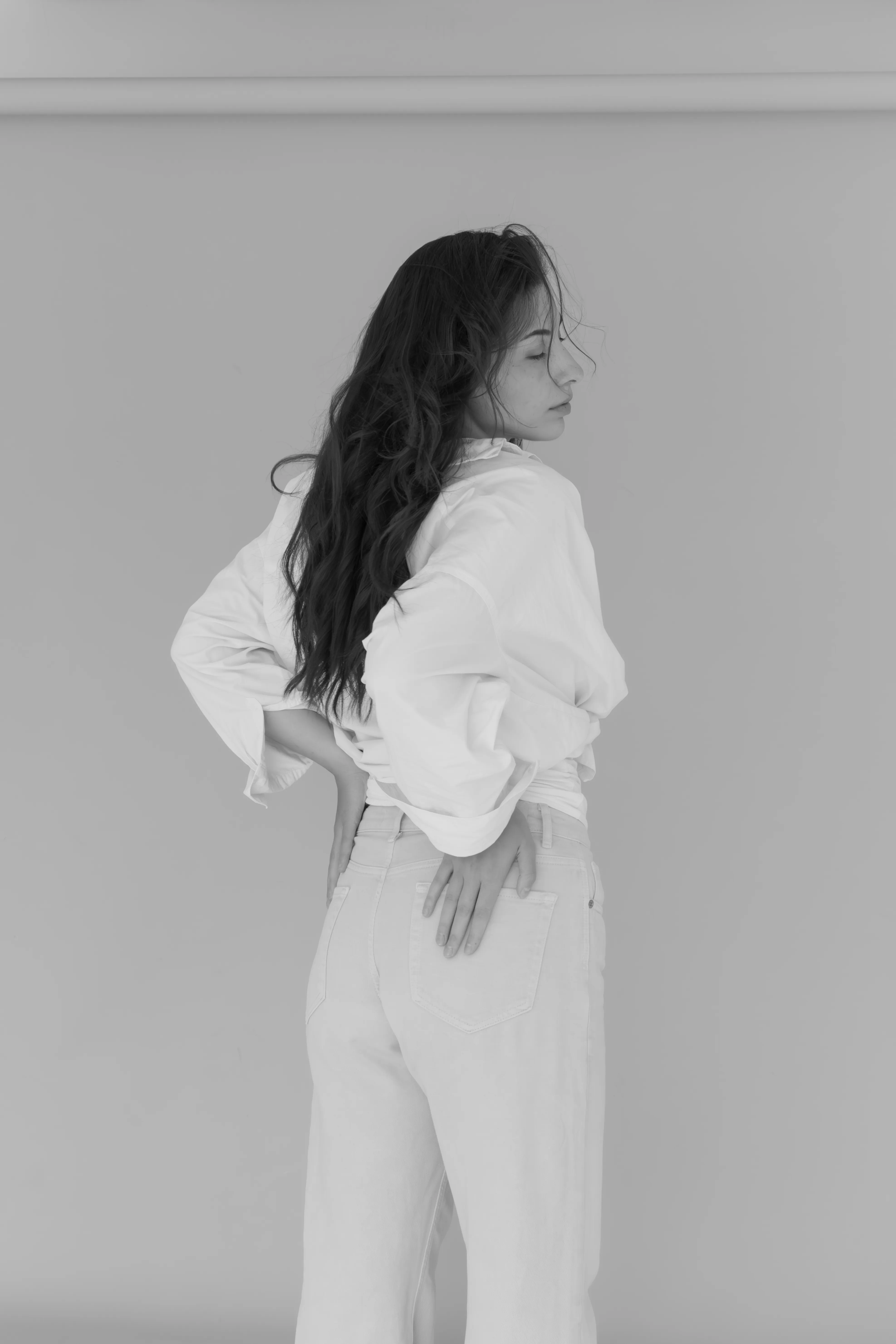 Woman in white outfit from behind in studio